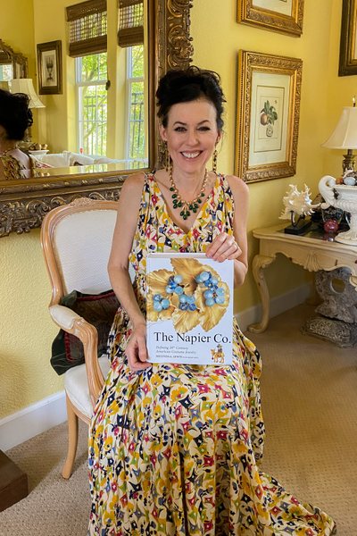 Melinda Lewis holding her book about the Napier jewely brand