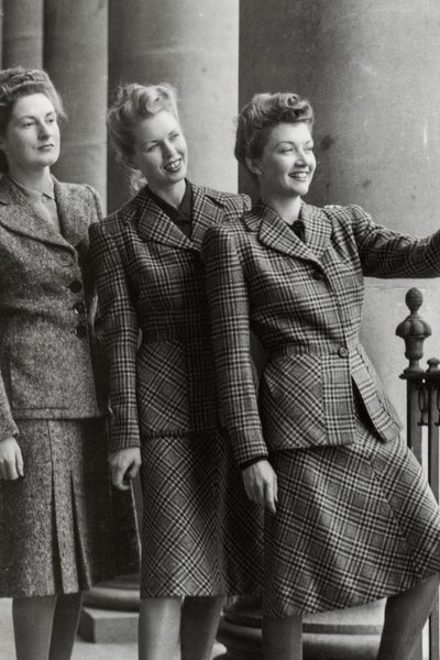 Three British women in WWII era skirt suits.