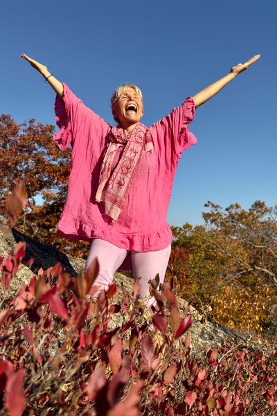 Andrea Diodati smiling and spreading her arms among the fall leaves