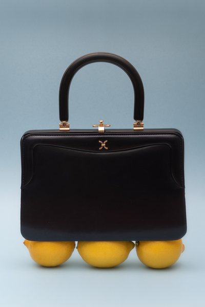 a 50s boxy black handbag displayed on top of three lemons