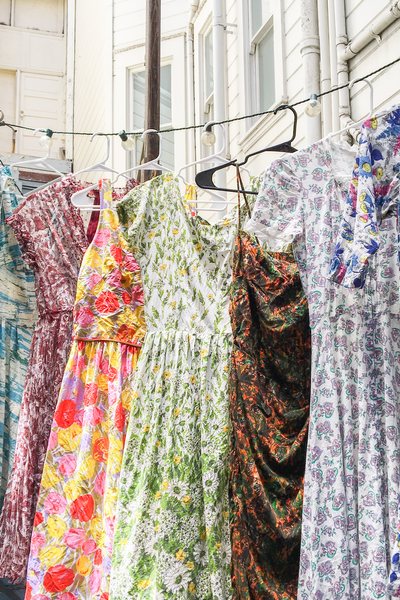 five colorful floral printed vintage 50s 60s dresses drying on a clothes line after washing