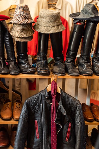 shelves full of black vintage leather boots and tweed hats and one black vintage motocycle leather jacket at the 282 Portobello vintage store in London