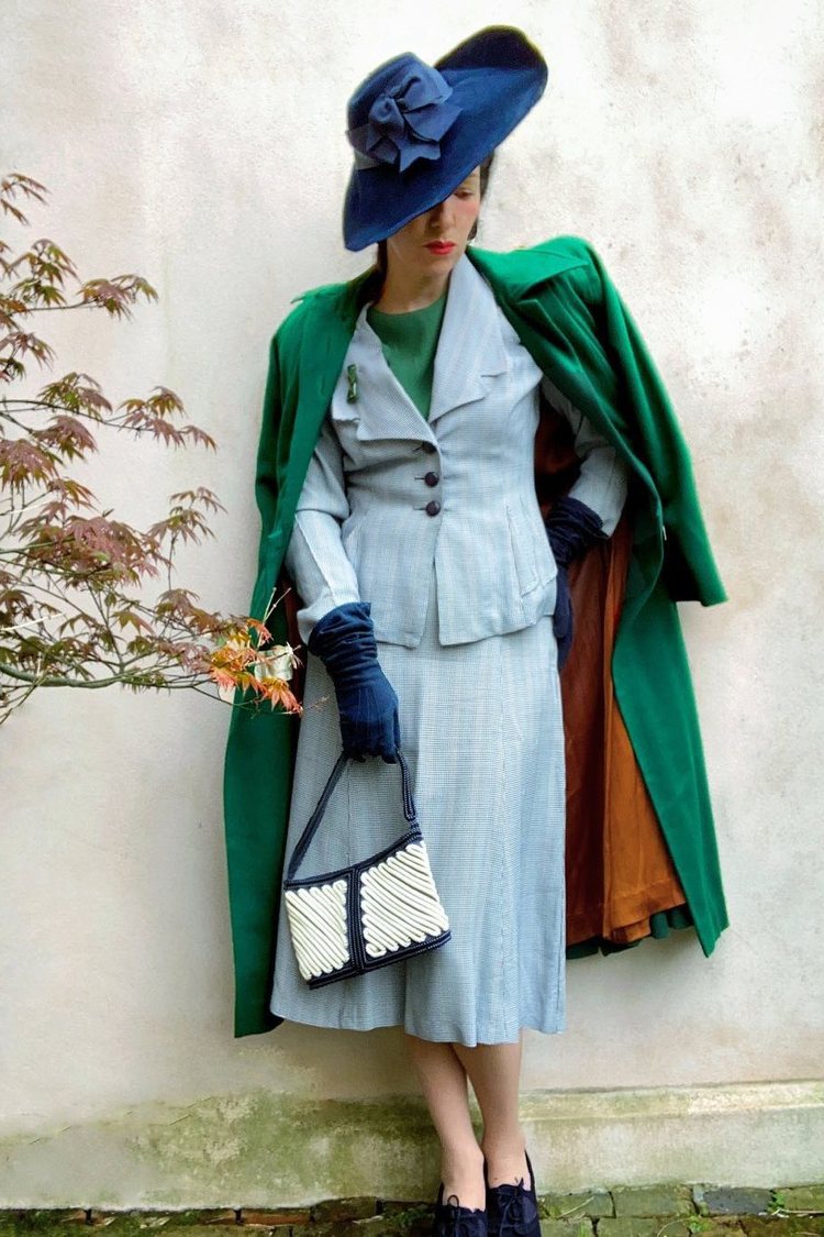 Olivia Bullock in a 40s blue hat, emerald green coat and pale blue skirt suit set.