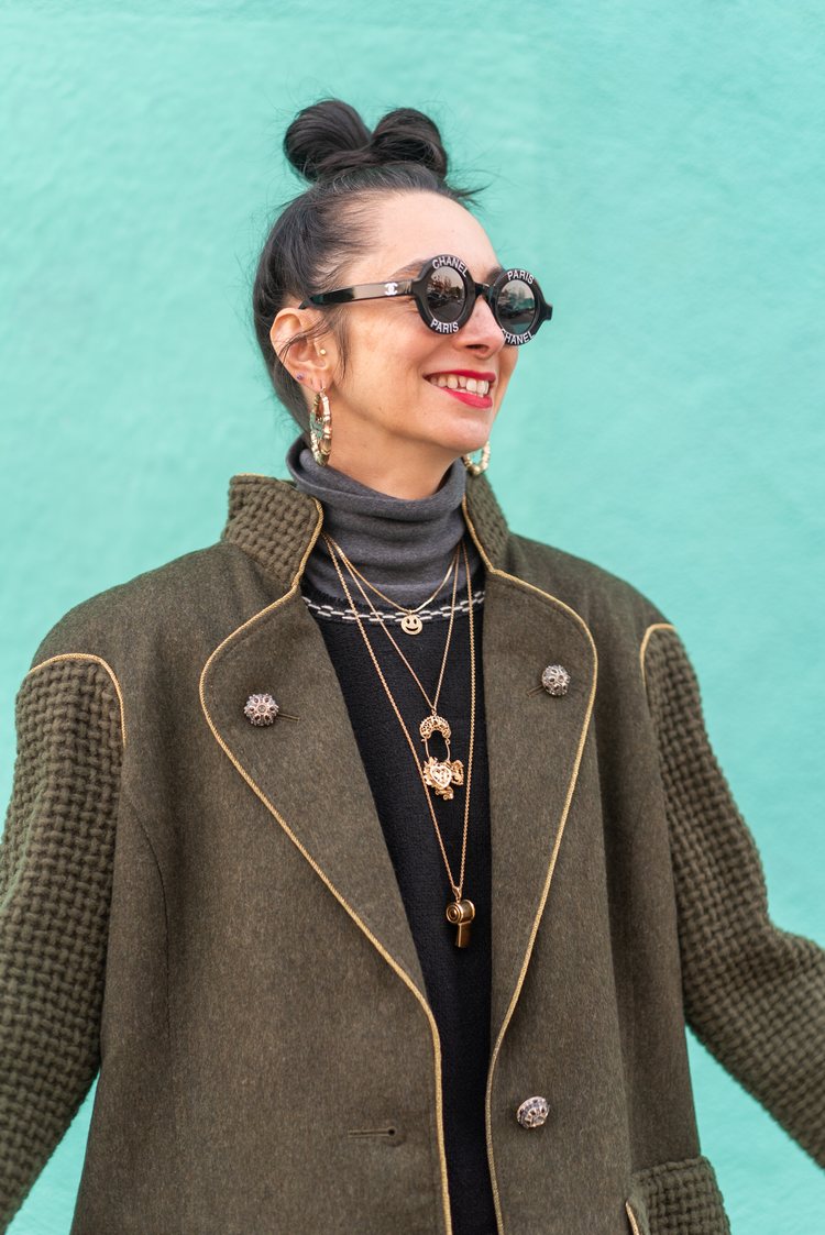 Vintage seller Liz Baca in round Chanel vintage sunglasses, L.L. Bean turtle neck from some random thrift store, Chanel top from Labels Luxury Consignment, and a woolen Chanel jacket. She also has a bunch of golden pendants and big golden hoops.