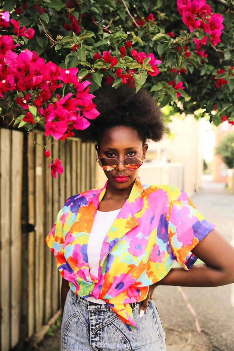 a model wearing a colorful 1980s print top and stone washed 1980s jeans