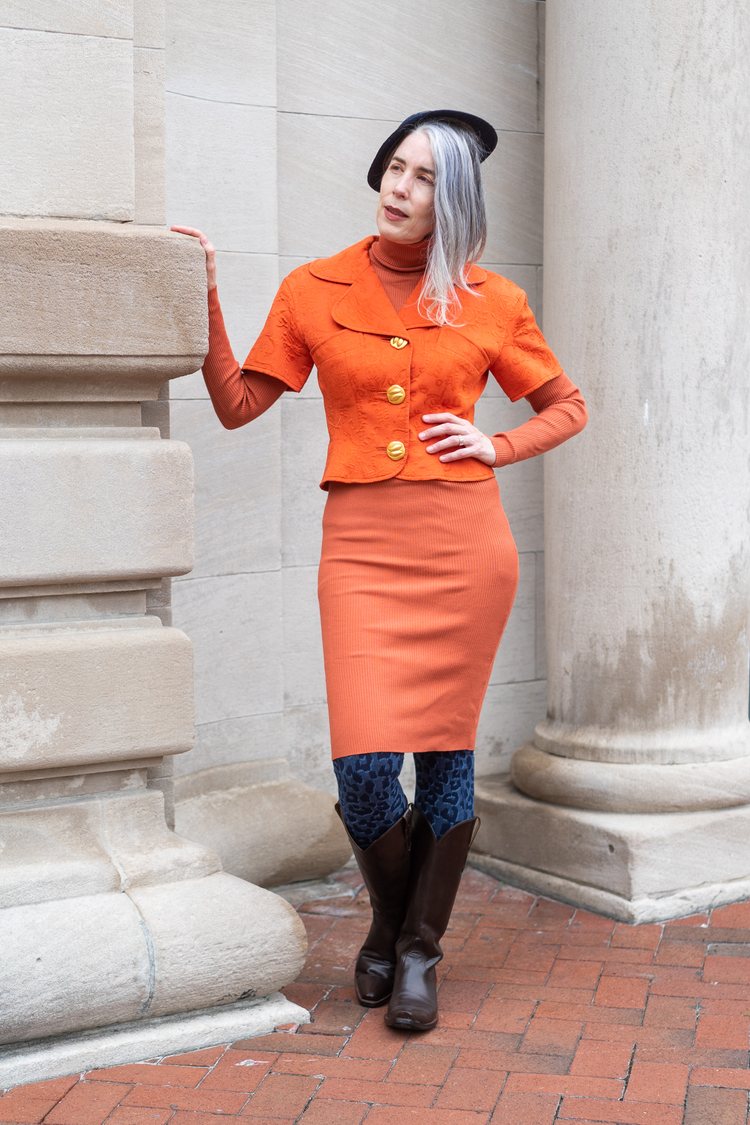 Australian American author Justine Larbalestier, 54, in an orange vintage outfit.