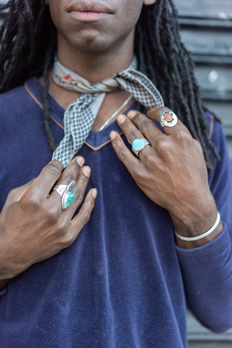 Jamee Jones wearing a grey silk neck scarf, three Western sterling silver rings with a 70s blue velour v-neck sweater