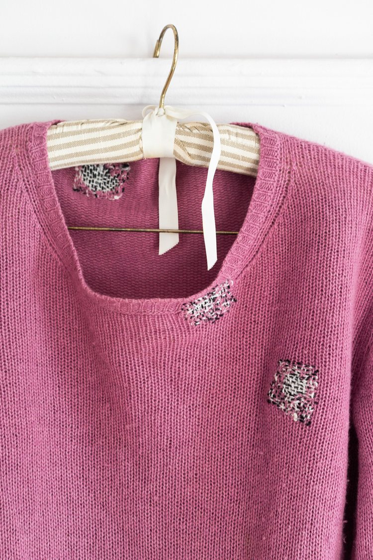 a raspberry pink woolen vintage sweater with several visible mends