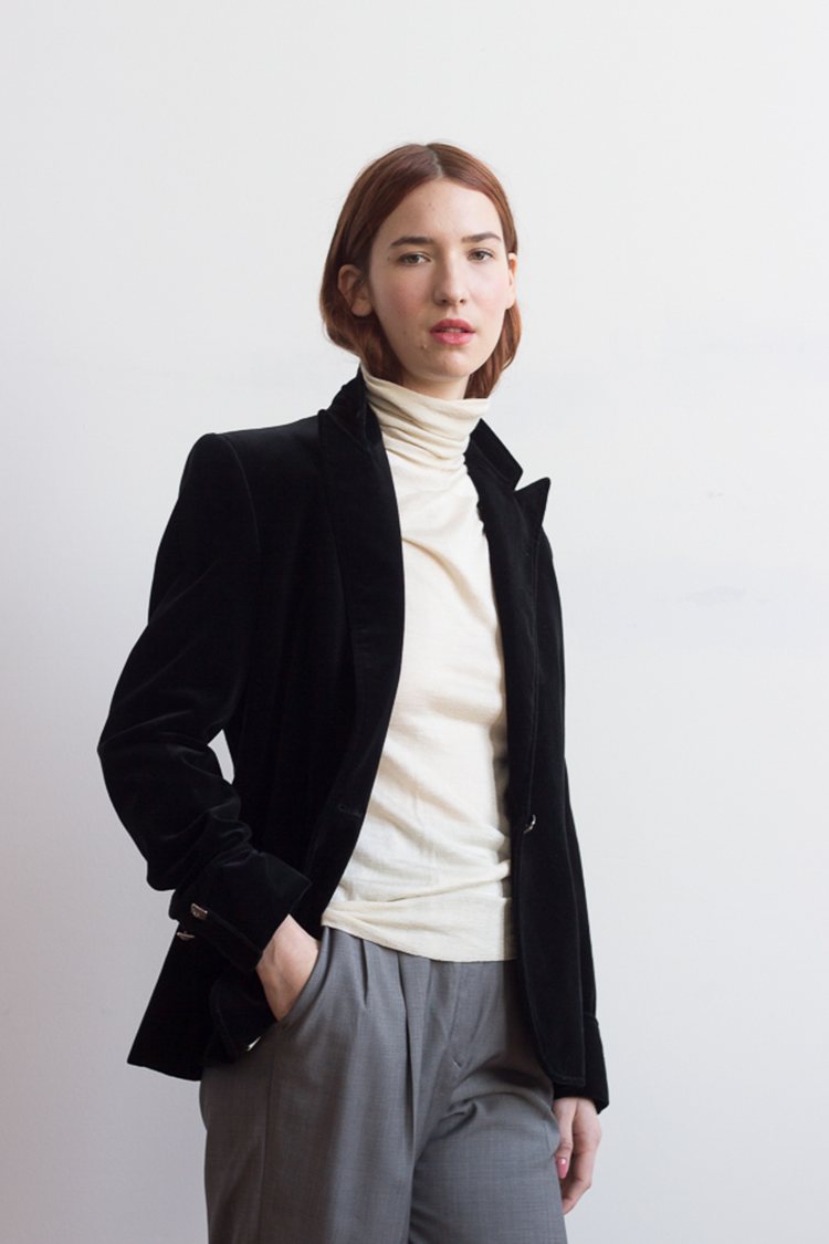 a model wearing a cream colored vintage turtleneck, black vintage blazer and grey vintage pants